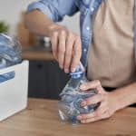 woman-crushing-plastic-bottles-for-recycling-2021-08-29-09-44-37-utc